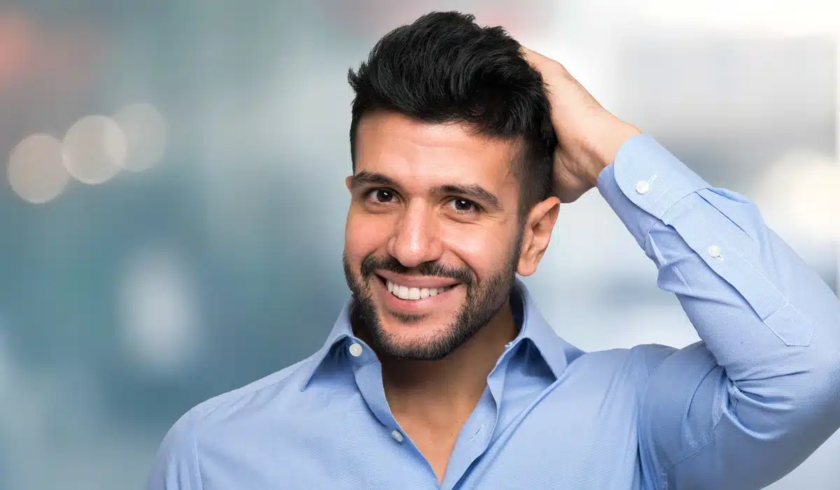 Right Clinic For Your Hair Transplant A man confidently touching his healthy, well-styled hair, representing the renewed self-esteem and natural-looking hair growth that a hair transplant can provide.