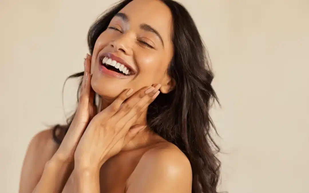 Beautiful laughing woman touching her skin with joy