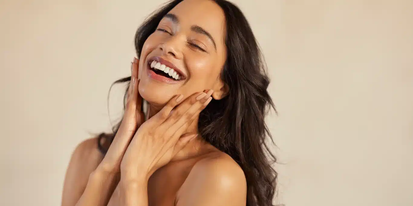 Beautiful laughing woman touching her skin with joy